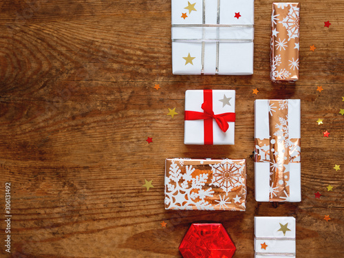 Christmas presents on shabby wooden background. Gifts in white and golden paper with bright golden riboons on with sparkling star confetti. photo