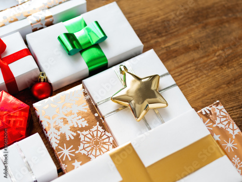 Christmas presents on shabby wooden background. Gifts in white and golden paper with bright golden riboons on with sparkling star confetti. photo