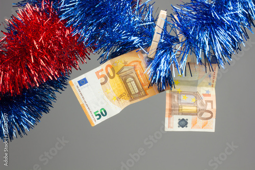 Dinero y navidades; billetes de dinero colgados y decorados con espumillón de navidad. photo