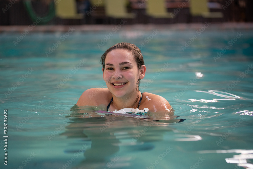 Teen Girl swimming in an indoor pool. Teen healthy lifestyle concept. 