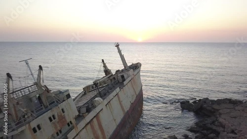 Aerial of cargo vessel shipwreck near rocky coast at sunset in Paphos district, Cyprus photo