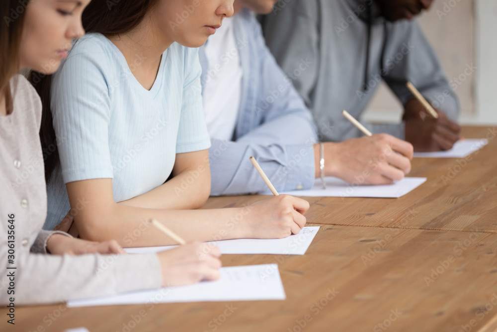 Close up mixed race students writing academic test. Close up mixed race students writing academic test.