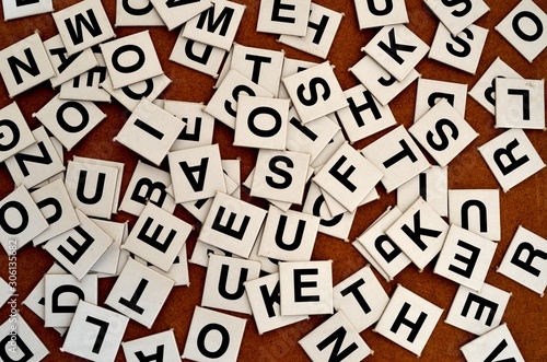 A pile of black letters tiles on brown card bord