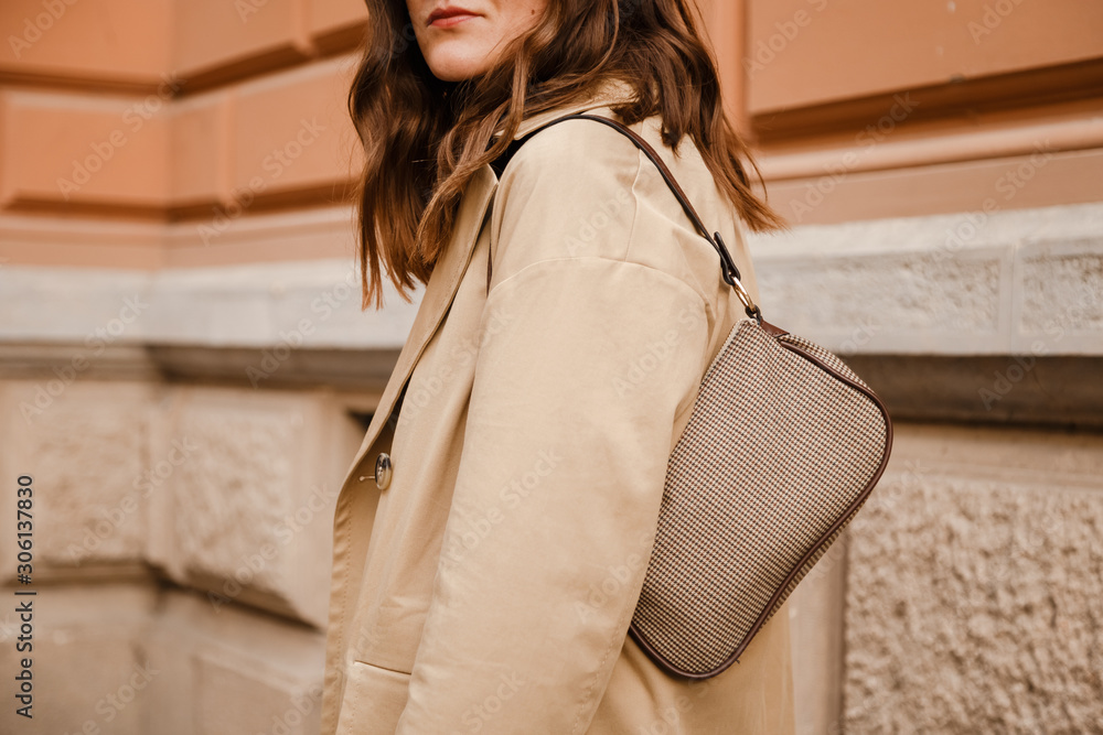 street style details. an attractive woman wearing a beige trench coat and 90s  pattern vintage shoulder mini bag, crossing the street. fashion outfit  perfect for autumn foto de Stock | Adobe Stock