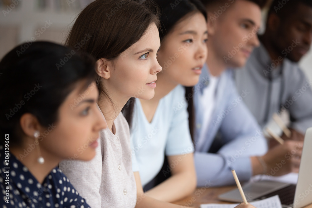 Focused group of mixed race students sitting together at lecture. Focused group of mixed race students sitting together at lecture.