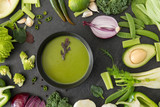 food, culinary and healthy eating concept - close up of different green vegetables and cream soup in ceramic bowl on slate stone background
