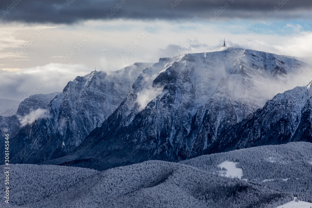 Beautiful mountain panorama in winter with fog and clouds. Bucegi mountains seen from Postavaru, Romania.