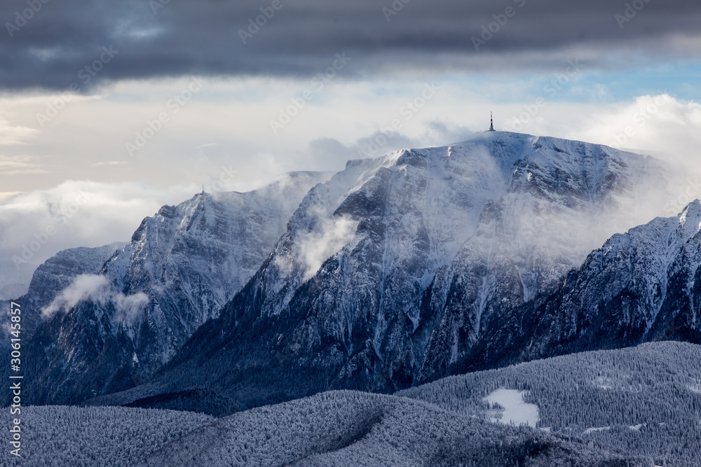 Fototapeta premium Beautiful mountain panorama in winter with fog and clouds. Bucegi mountains seen from Postavaru, Romania.