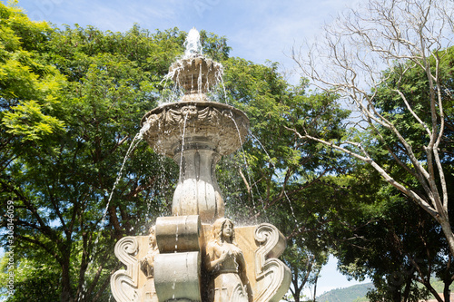 Fountain of the sirens in Antigua Guatemala- fountain in the middle of a park surrounded by trees in colonial city