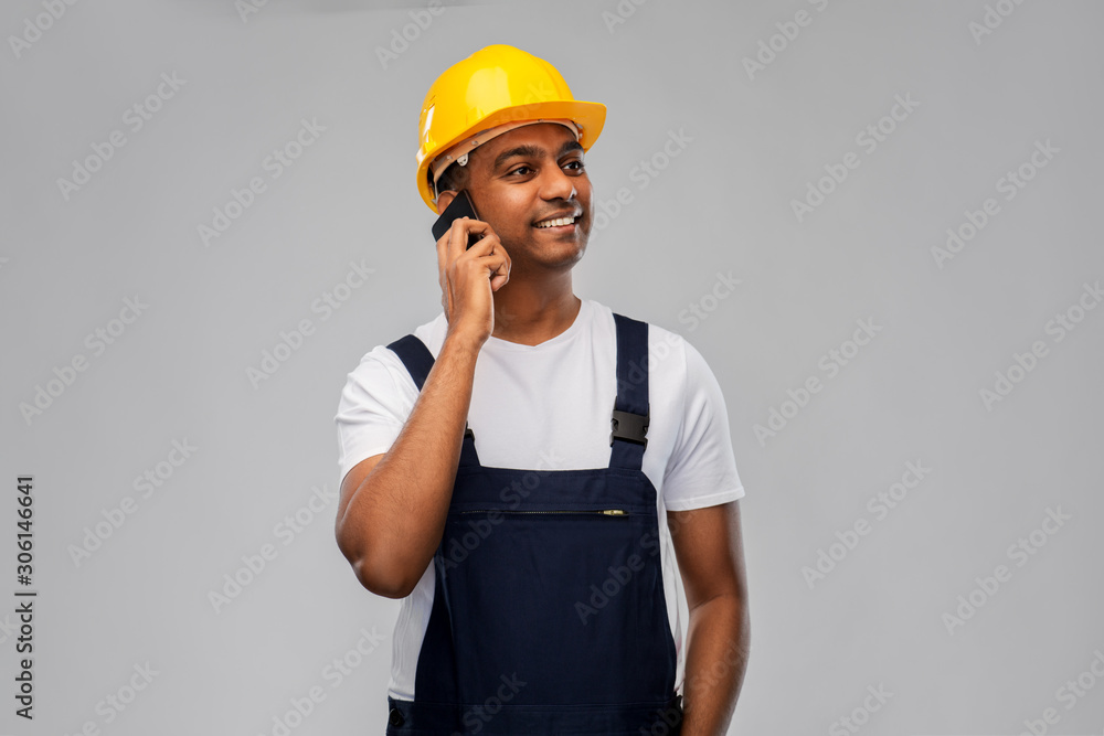 profession, construction and building - happy smiling indian worker or builder in helmet calling on smartphone over grey background profession, construction and building - happy smiling indian worker or builder in helmet calling on smartphone over grey background