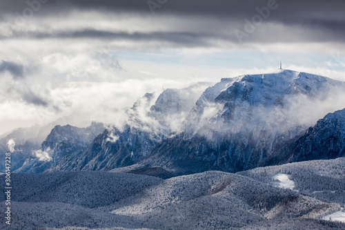 Beautiful mountain panorama in winter with fog and clouds. Bucegi mountains seen from Postavaru, Romania.
