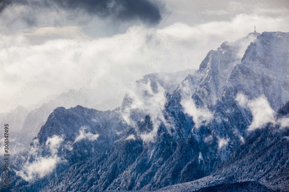 Beautiful mountain panorama in winter with fog and clouds. Bucegi mountains seen from Postavaru, Romania.