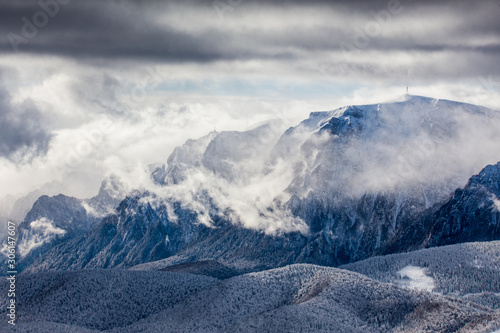 Beautiful mountain panorama in winter with fog and clouds. Bucegi mountains seen from Postavaru, Romania.