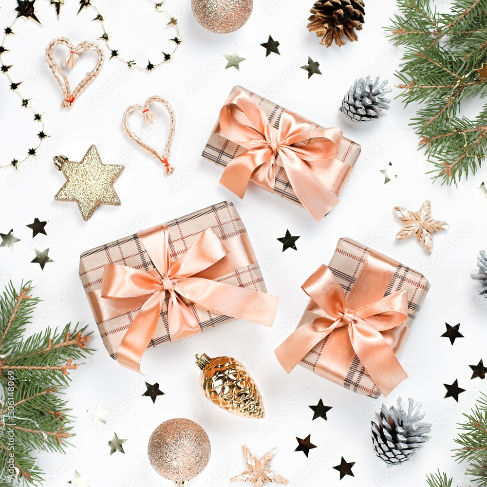 Golden baubles, gifts wrapped in craft paper, pine branches, confetti on white wood. Christmas flat lay with decorations and presents on white wooden background, copy space, top view. Golden baubles, gifts wrapped in craft paper, pine branches, confetti on white wood. Christmas flat lay with decorations and presents on white wooden background, copy space, top view.
