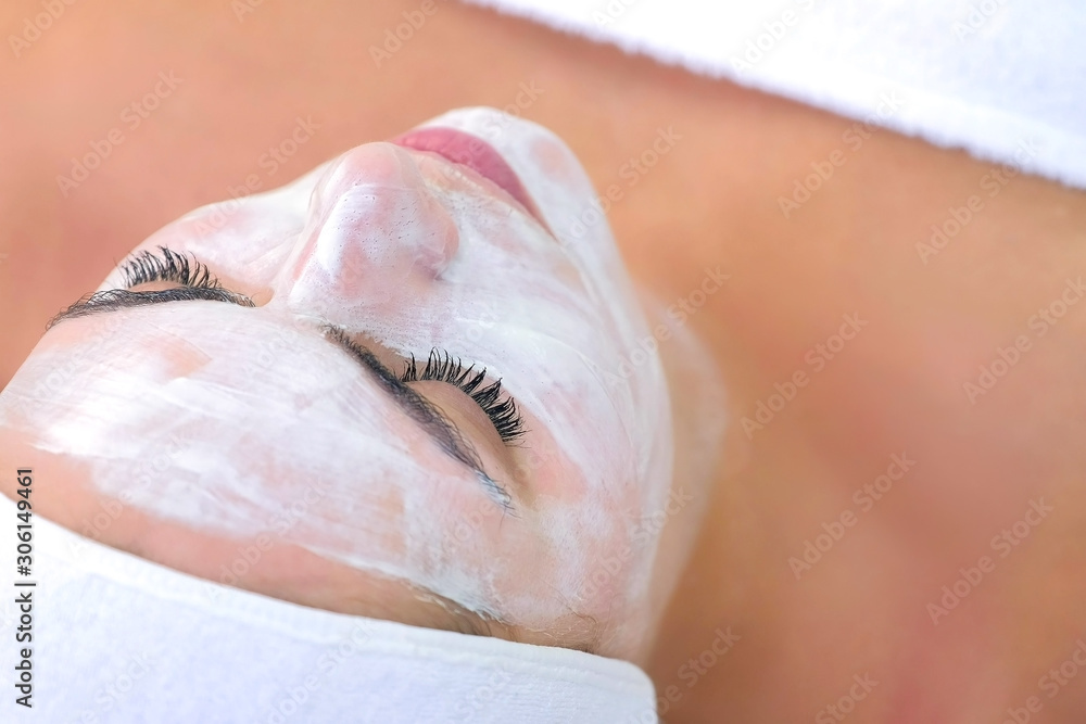 Portrait of woman laying in spa cosmetology salon with white mask on face. Beauty facial skincare procedure to patient in cosmetology clinic, face closeup. Beauty industry concept. Portrait of woman laying in spa cosmetology salon with white mask on face. Beauty facial skincare procedure to patient in cosmetology clinic, face closeup. Beauty industry concept.