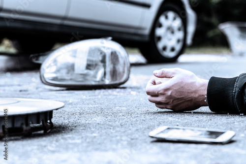 Canvas Print Human's hand on the ground next to broke car mirror and mobile phone after a cra
