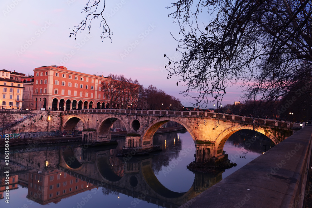 Evening on the embankment by the Tiber River. Rome. Italy. Urban landscape of bridges across the river.