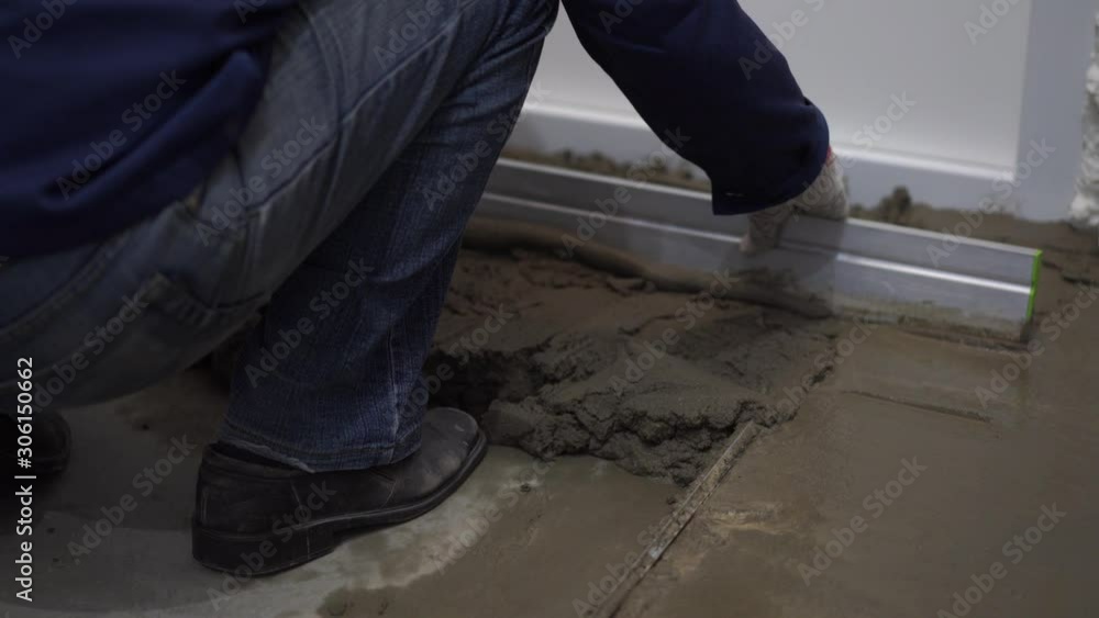 repair of apartments and houses. the builder pours and levels the cement screed on the floor. repair of apartments and houses. the builder pours and levels the cement screed on the floor.