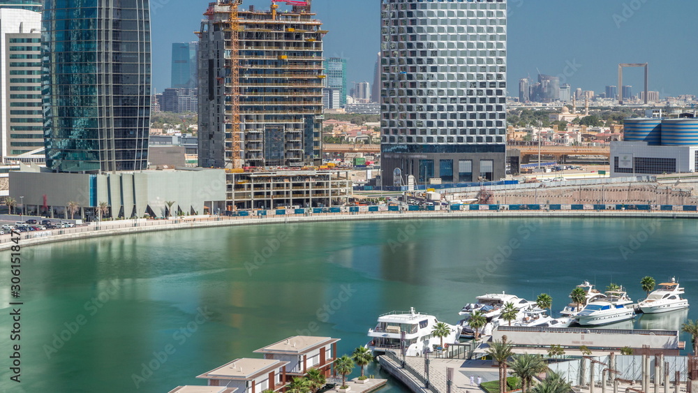 Fototapeta premium Skyscrapers near canal in Dubai with blue sky aerial timelapse