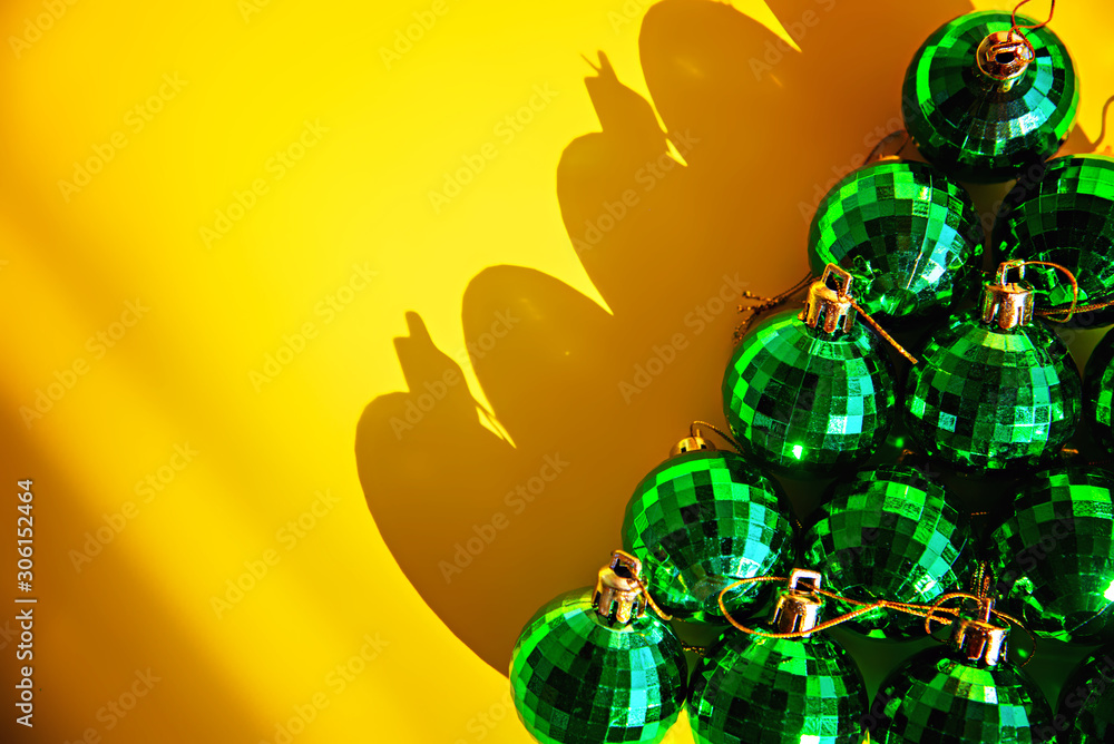 Green strobe Christmas balls lay on a yellow background