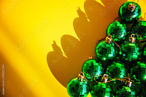 Green strobe Christmas balls lay on a yellow background