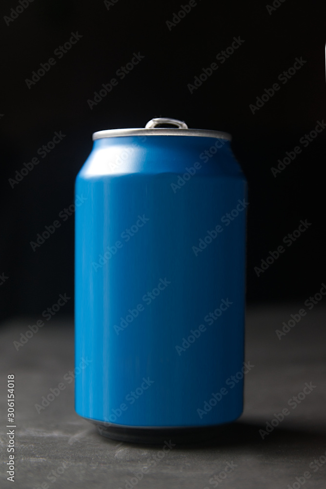 Isolated aluminium can mockup on a black wooden table against a dark background. Empty copy space for Editor's text. Isolated aluminium can mockup on a black wooden table against a dark background. Empty copy space for Editor's text.