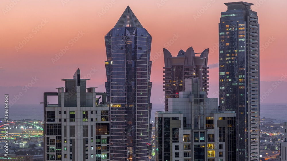 Obraz premium Widok na oświetlone wieżowce ze światłami z okien w Dubaju o zachodzie słońca anteny timelapse