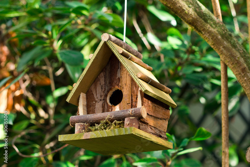 Wooden birdhouse hanging on a tree close-up. Nature help concept