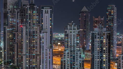 Modern residential and office complex with many towers aerial night timelapse at Business Bay, Dubai, UAE.