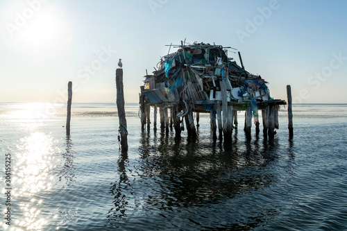 Fotografia Stilt house on the sea full of plastic and trash