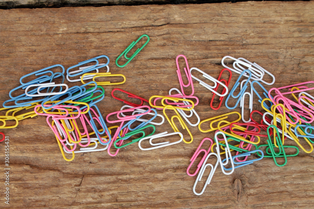 Paper clips of different colors on a wooden table. Paper clips of different colors on a wooden table.
