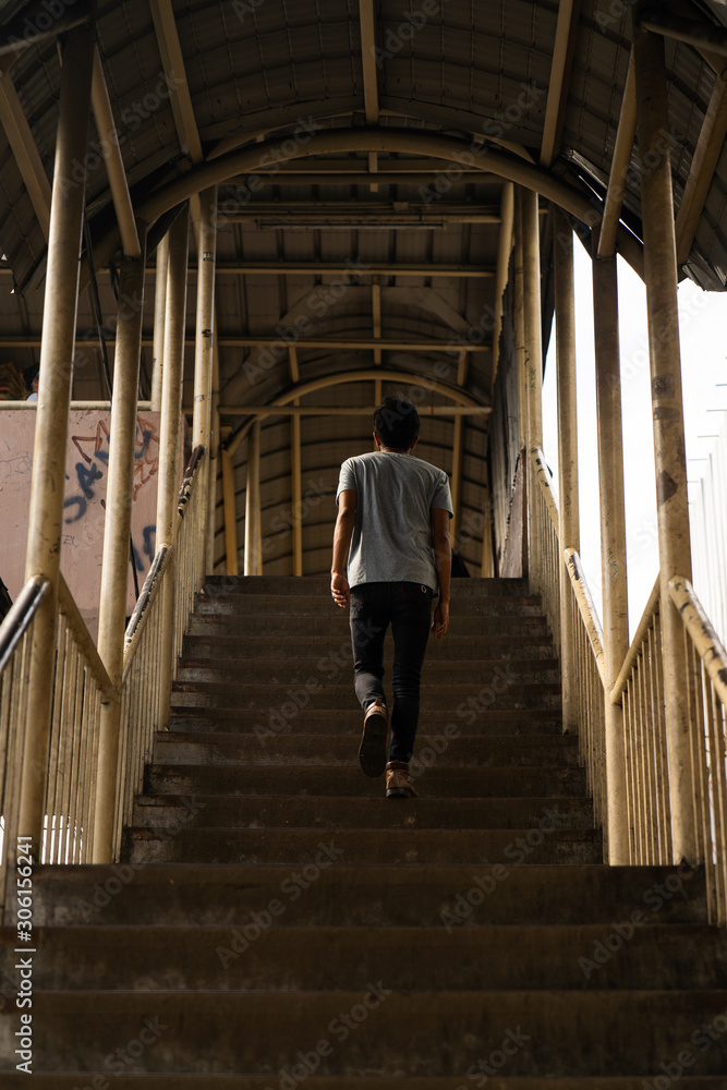 A man walks up the staircase of a footbridge; urban setting