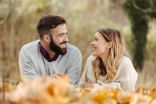 Smiling couple relaxing in nature while lying down and talking to each other