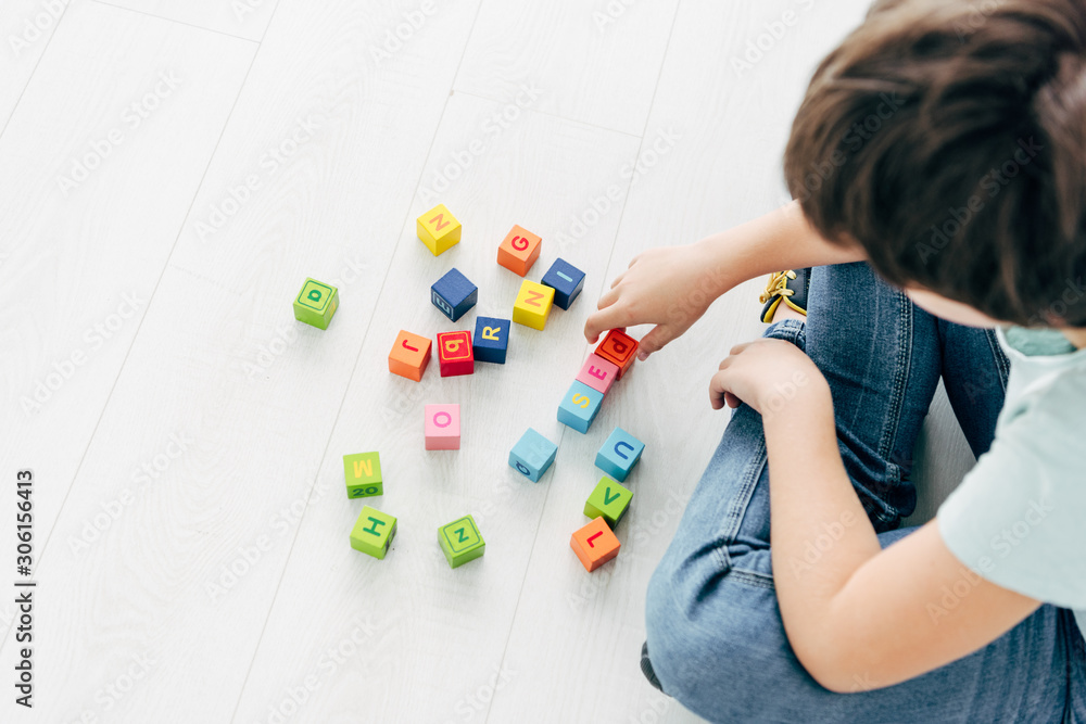 cropped view of kid with dyslexia playing with colorful building blocks cropped view of kid with dyslexia playing with colorful building blocks