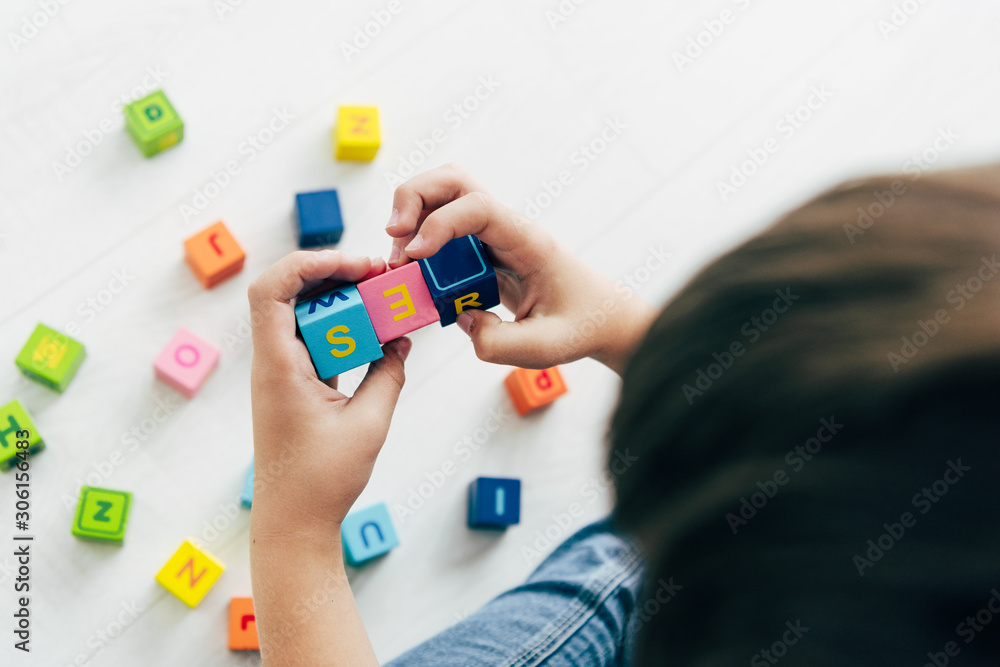 cropped view of kid with dyslexia playing with colorful building blocks