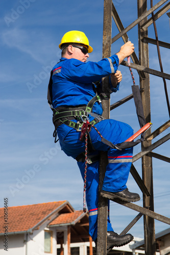 Electrician with safety belt climb on lamppost