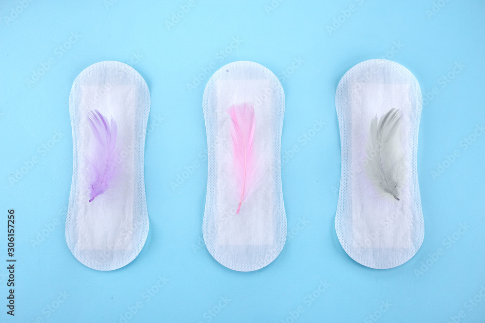 Menstrual pad with feathers on color background Menstrual pad with feathers on color background