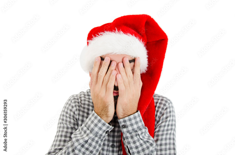 Young man with Santa Claus hat cover his face with his hands feeling lonely and sad for New Year and Christmas holiday depression concept. Isolated on white background Young man with Santa Claus hat cover his face with his hands feeling lonely and sad for New Year and Christmas holiday depression concept. Isolated on white background
