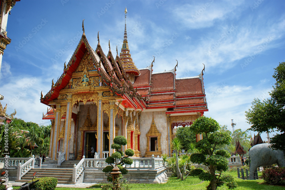 View of the traditional Asian pagoda. A white building with gold trim and a red roof against the sky. Buddhist temple facade in Thailand.