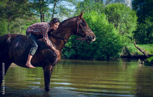 portrait of girl riding red trakehner stallion horse in the river in the summer © vprotastchik