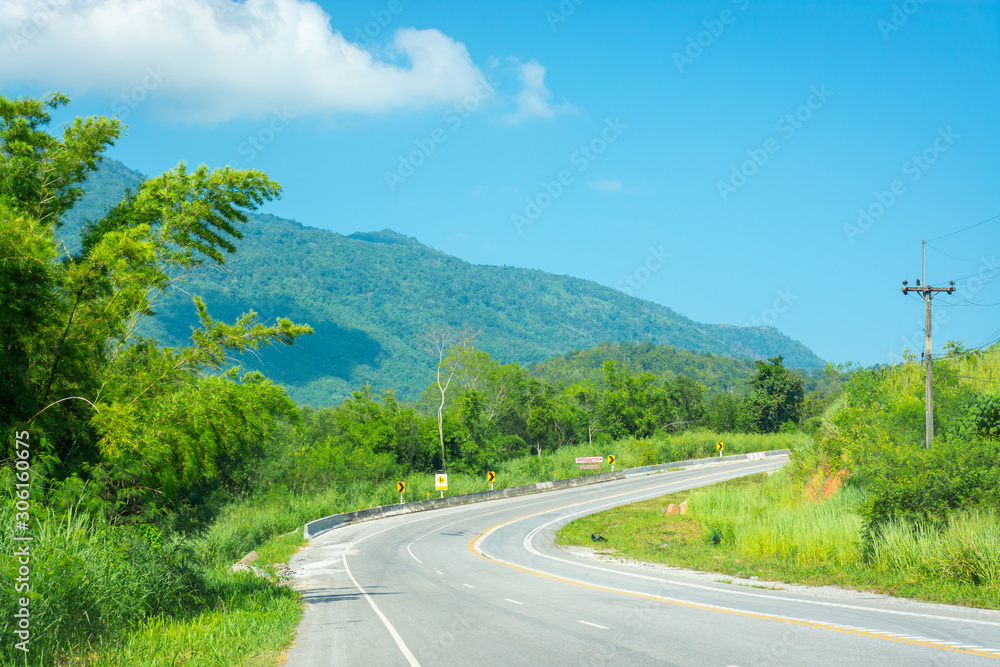 A steep curve of the road against the backdrop of the mountains. 