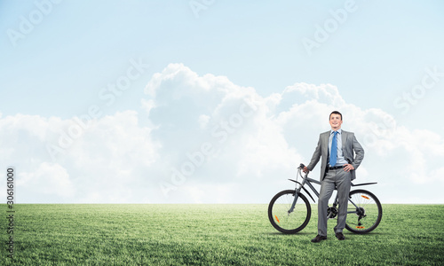 Fototapeta Naklejka Na Ścianę i Meble -  Smiling businessman with bicycle outdoors