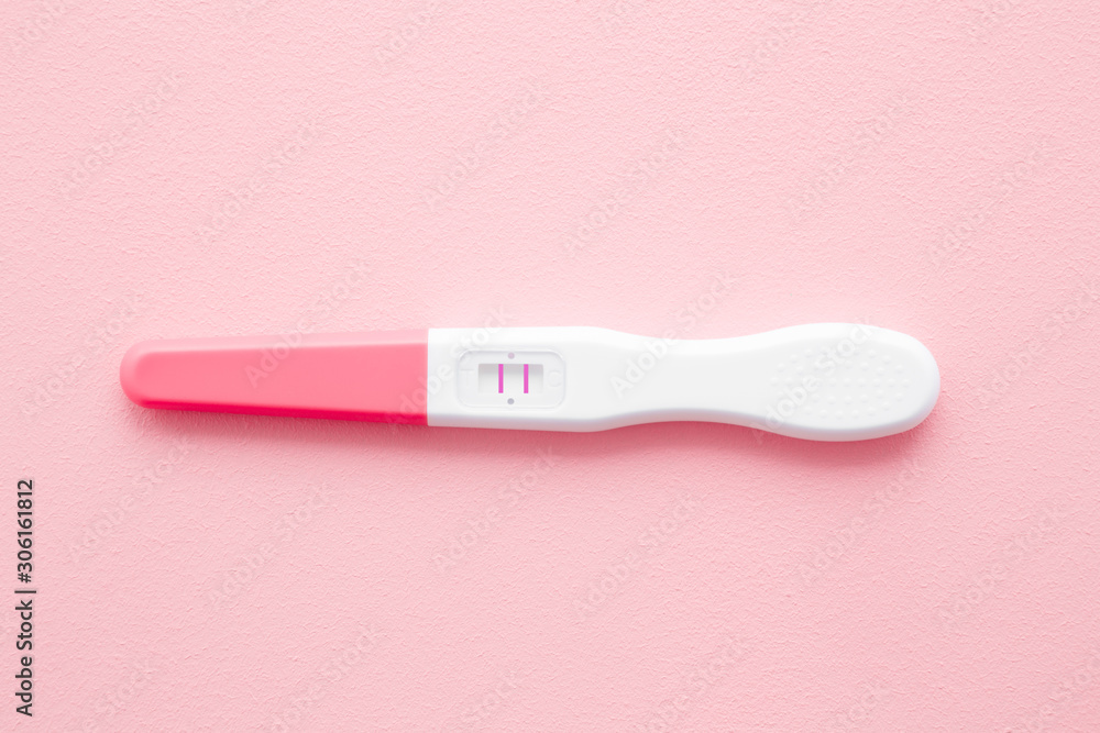 Pregnancy test with two stripes on pastel pink background. Positive result. Closeup. Top down view. Pregnancy test with two stripes on pastel pink background. Positive result. Closeup. Top down view.