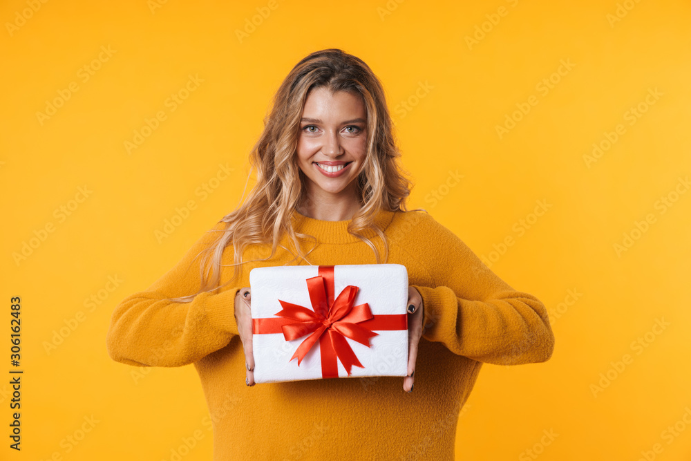 Fototapeta premium Image of beautiful blonde woman in warm sweater smiling and holding present box