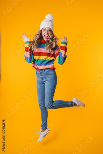 Full length image of cheerful woman in winter hat laughing at camera