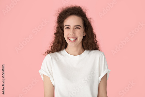 Portrait of smiling millennial girl posing on pink background