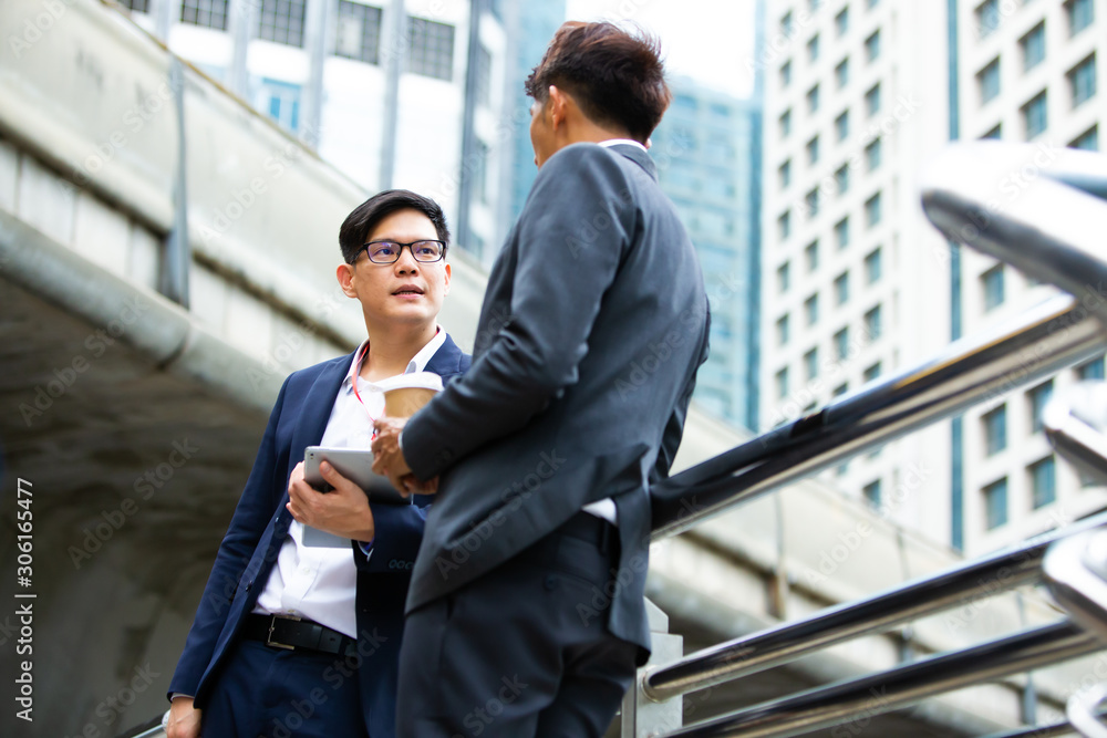 Image of two Asian young businessmen walk and talk in the city Image of two Asian young businessmen walk and talk in the city