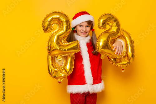 Girl dressed as Santa holding balloons 2020