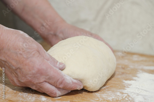 Hands of an adult woman cooking dough on  wooden background. Food concept