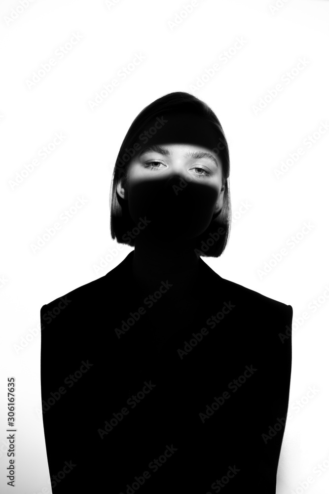 Fashionable beauty portrait. Black silhouette on white background. Girl with a spot of light on her face. Fashionable beauty portrait. Black silhouette on white background. Girl with a spot of light on her face.